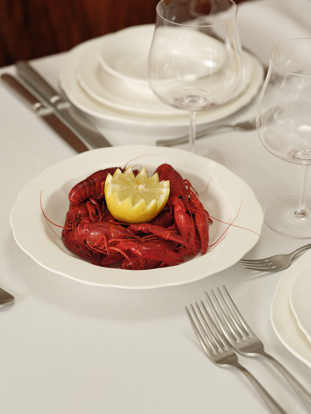 Plated crawfish with lemon on a white plate on a dining table.
