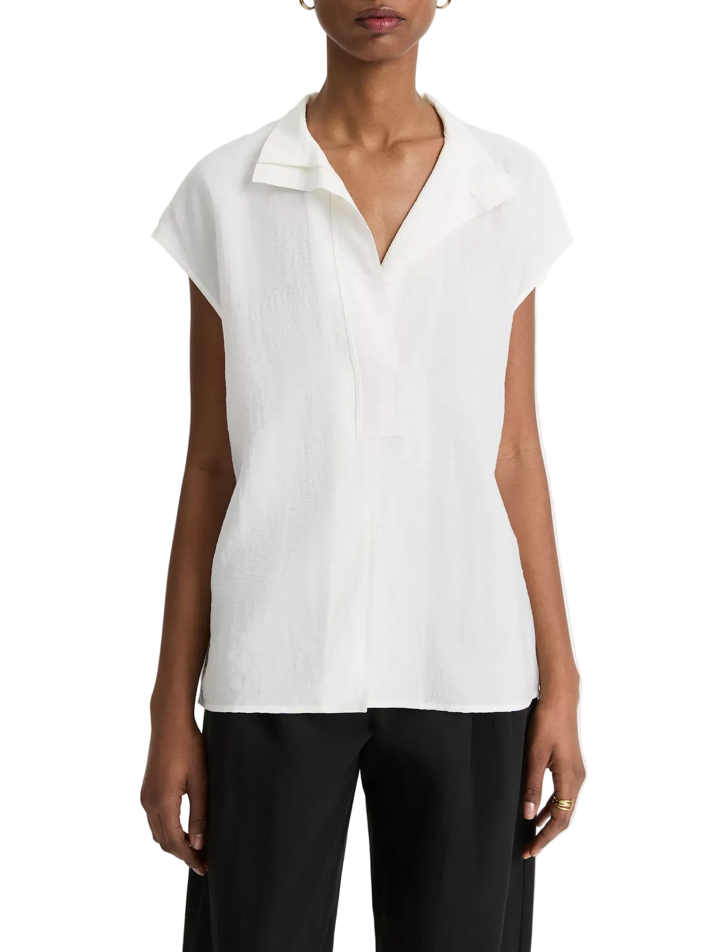 A woman wearing a white cap sleeve blouse with a collar stand, paired with black pants.