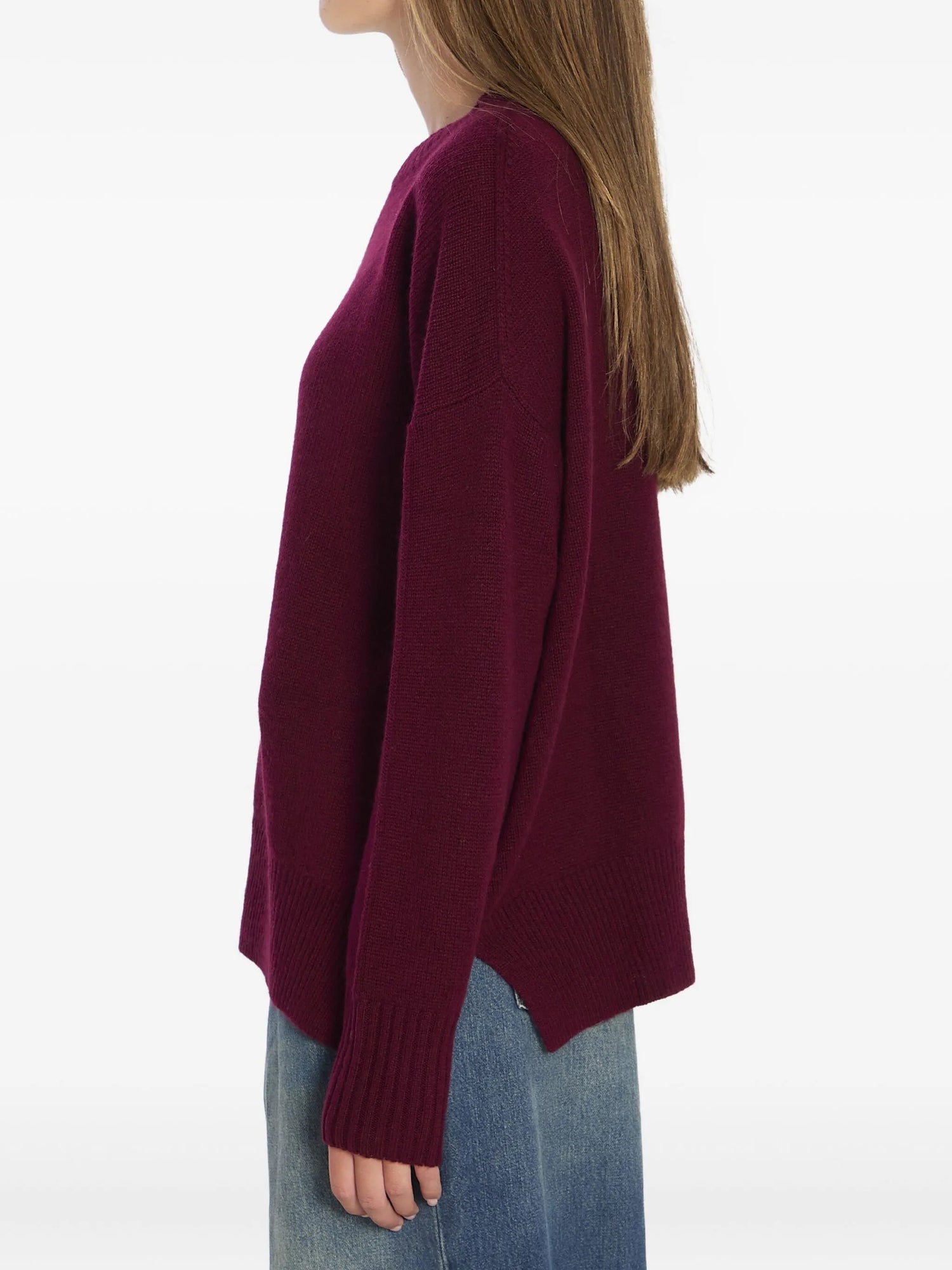 Person wearing a burgundy sweater and blue jeans on a white background