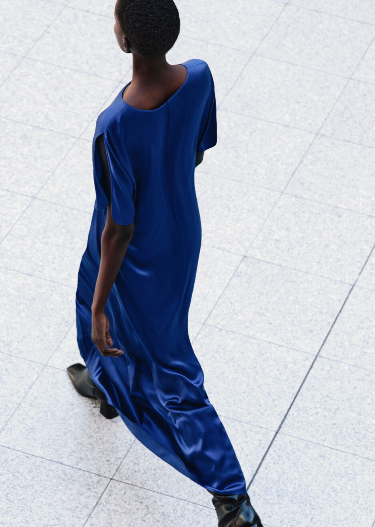 Person wearing a blue dress walking on a white tiled floor