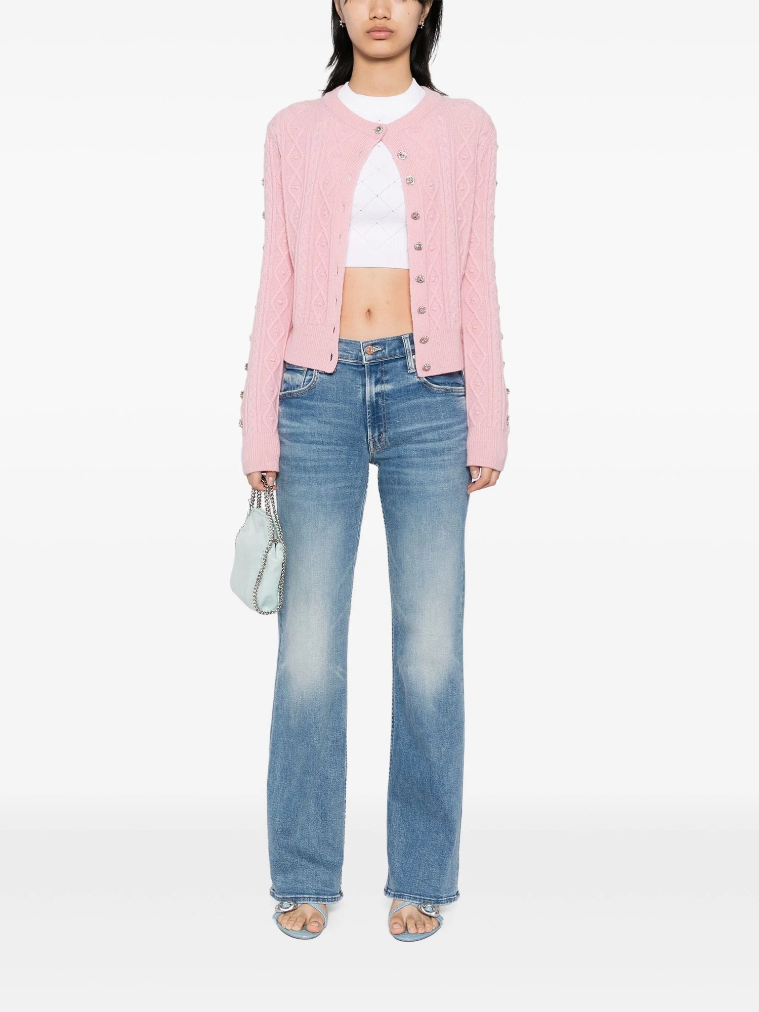 Person wearing a pink cardigan, white top, and blue jeans on a white background