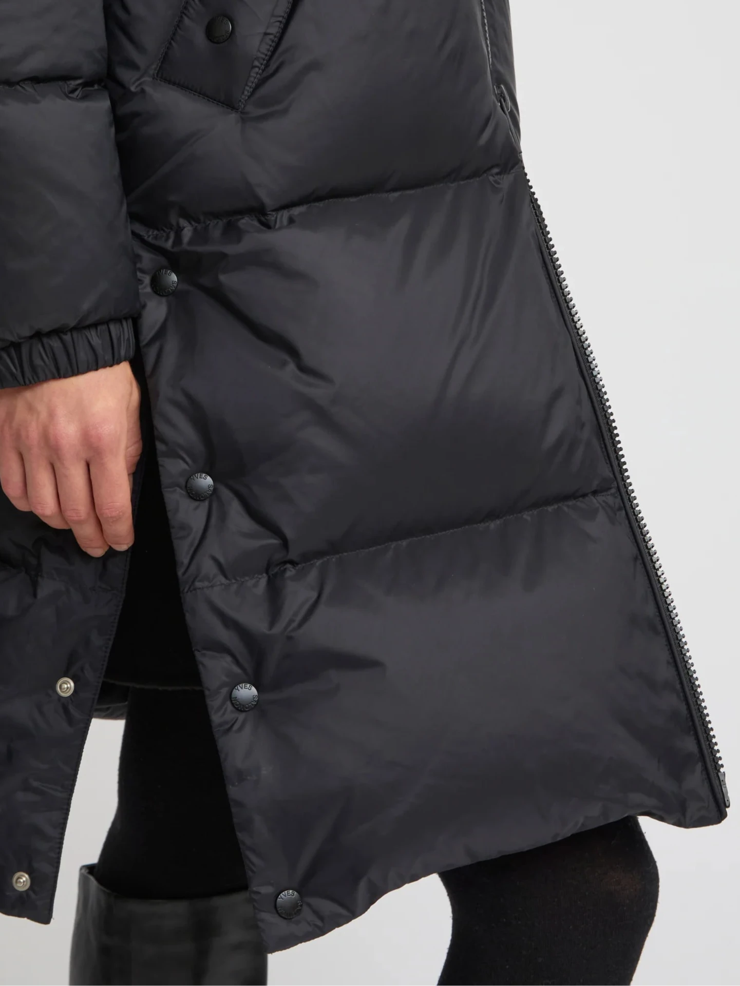 Black puffer coat with buttons on a light gray background