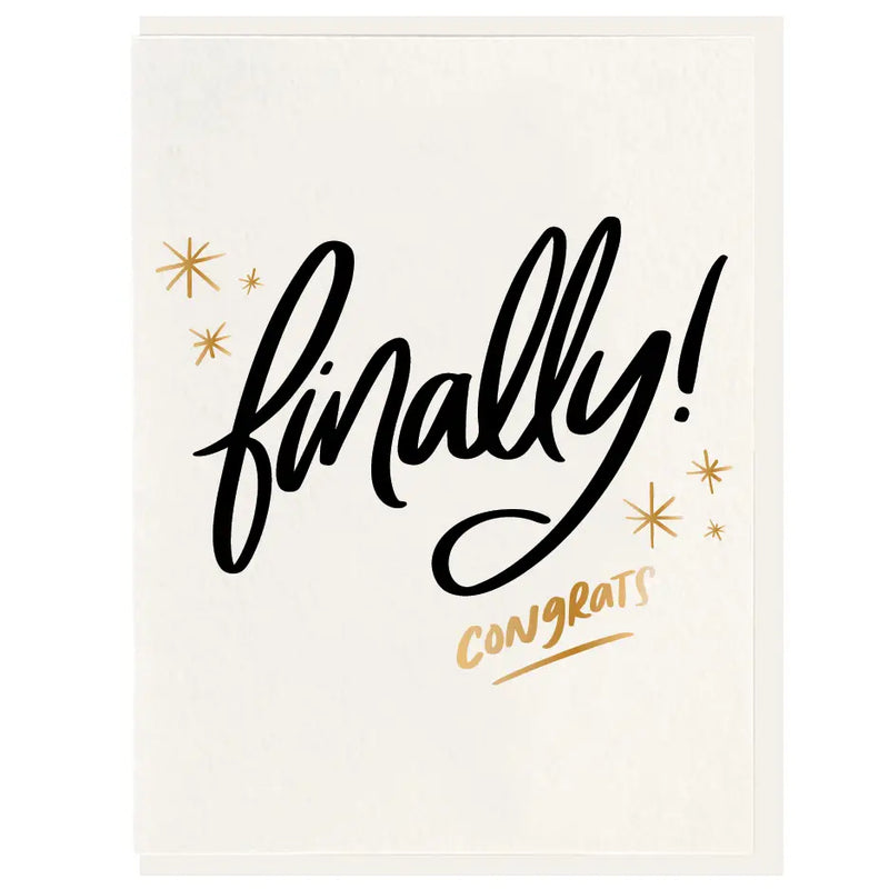 A folded greeting card with the words 'finally! congrats' hand-illustrated in black, accompanied by small gold stars, on the front. It comes with an envelope.