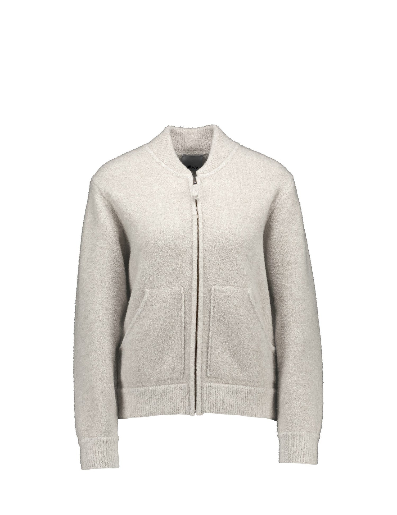 A light beige zip-up cardigan sweater with a ribbed collar, cuffs, and hem, featuring two front patch pockets, shown against a plain white background.