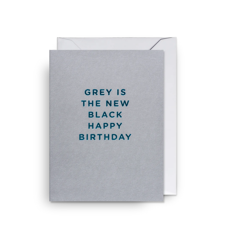 A mini sized greeting card with the text 'GREY IS THE NEW BLACK HAPPY BIRTHDAY' printed on it, accompanied by a matching envelope, against a white background.