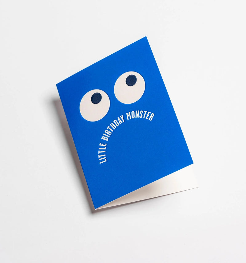 Blue card with white eyes and 'Little Birthday Monster' text on a light gray background