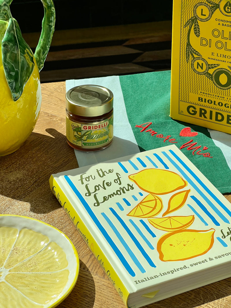 Book titled 'For the Love of Lemons' with a jar of(Gridelli) on a wooden surface.