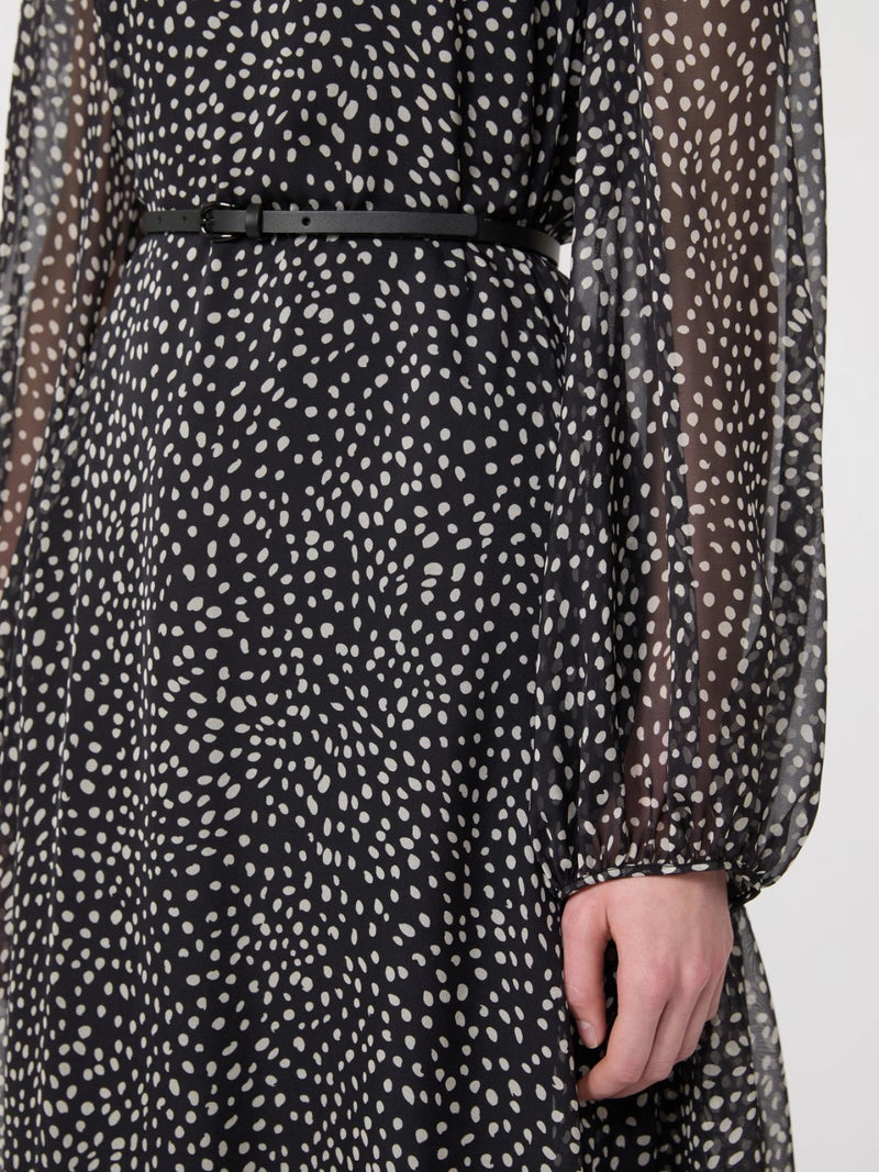 Black dress with white polka dot pattern and sheer sleeves on a plain background