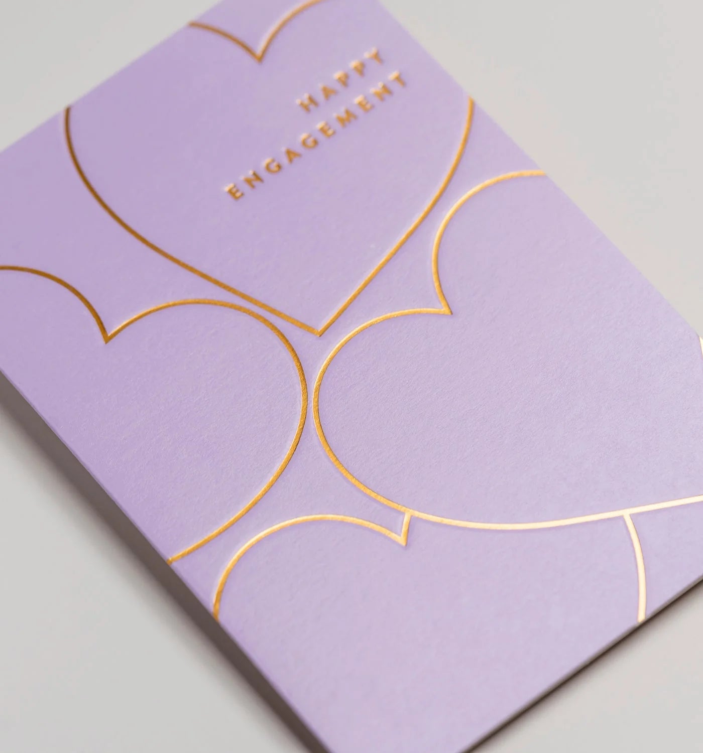 Purple card with gold heart designs and 'Happy Engagement' text on a light gray background