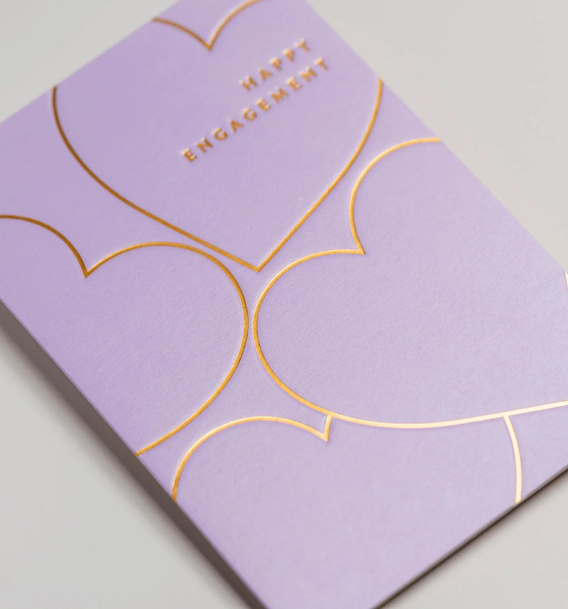 Purple card with gold heart designs and 'Happy Engagement' text on a light gray background