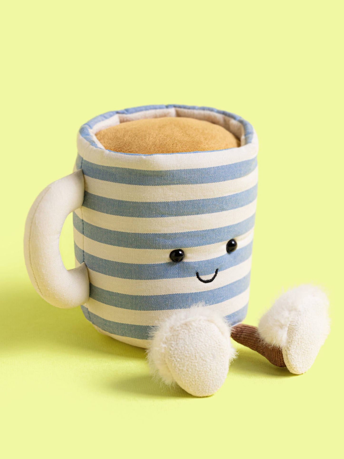 Plush mug with striped pattern and face on a yellow background