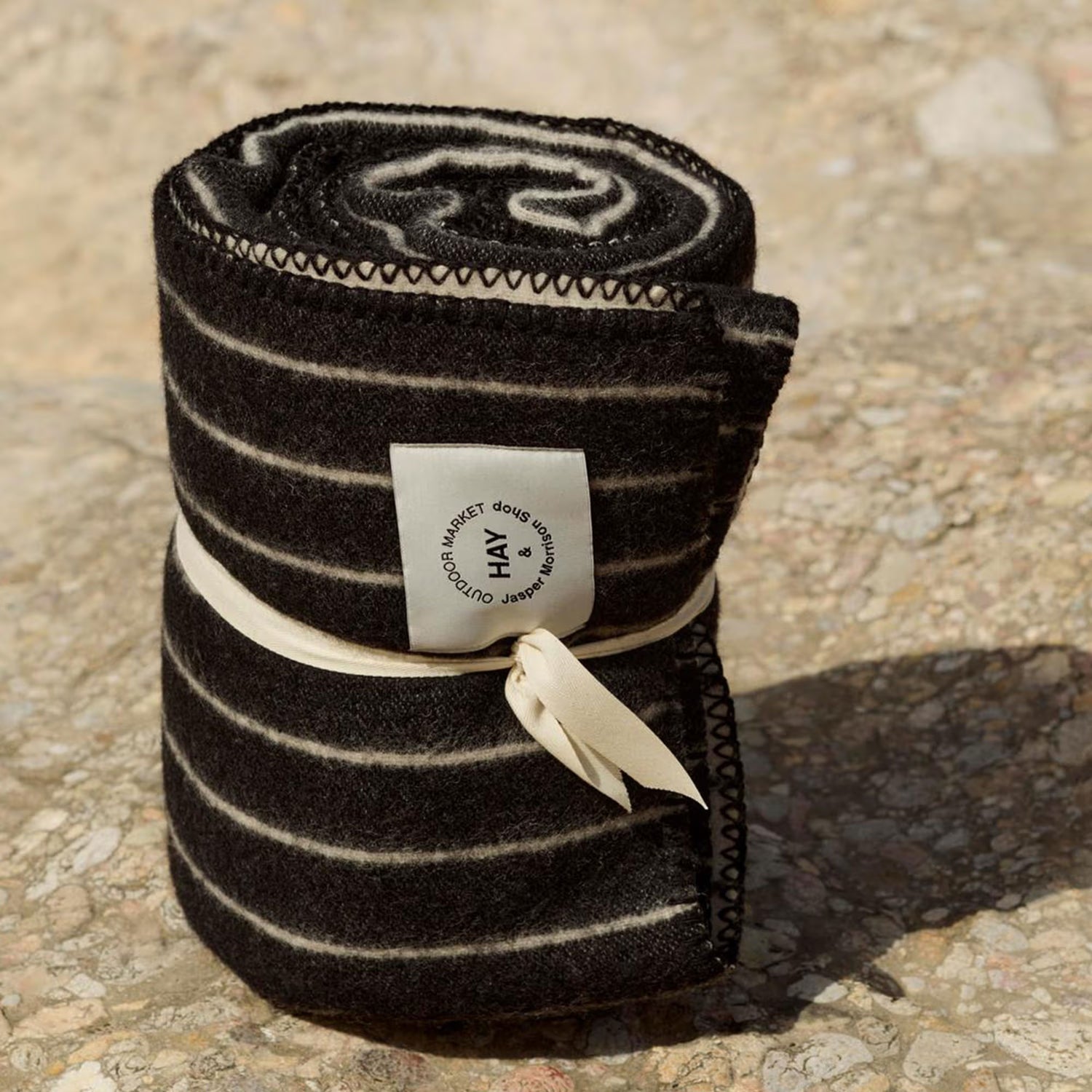 Rolled-up black and white striped blanket with a label on a textured surface