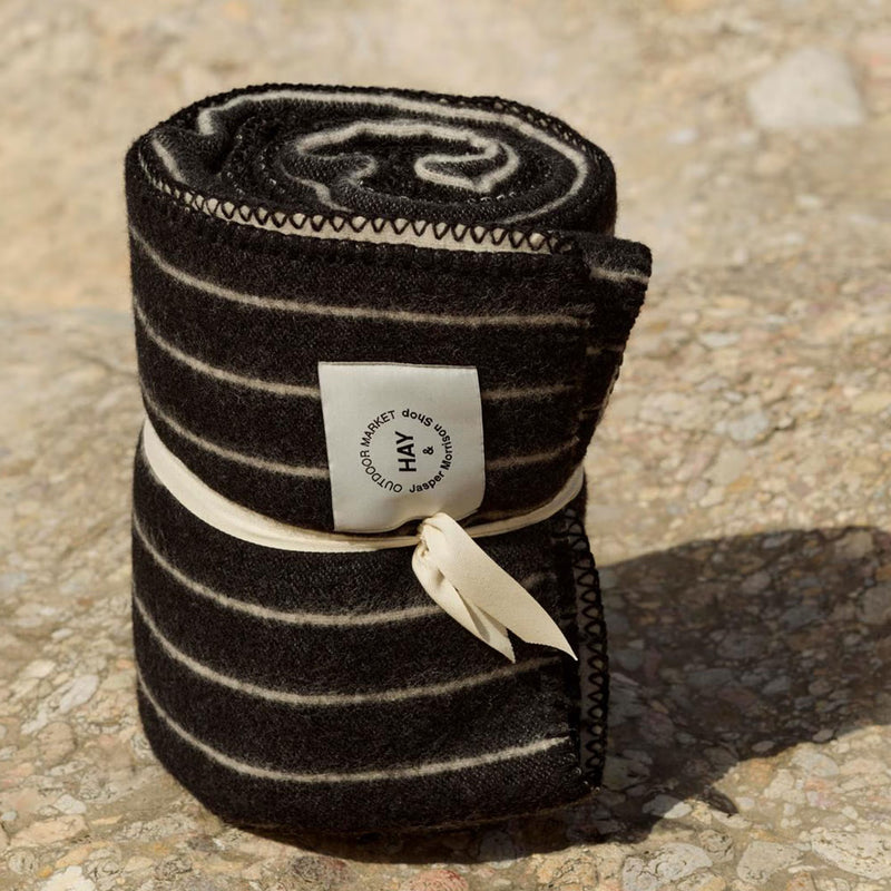 Rolled-up black and white striped blanket with a label on a textured surface