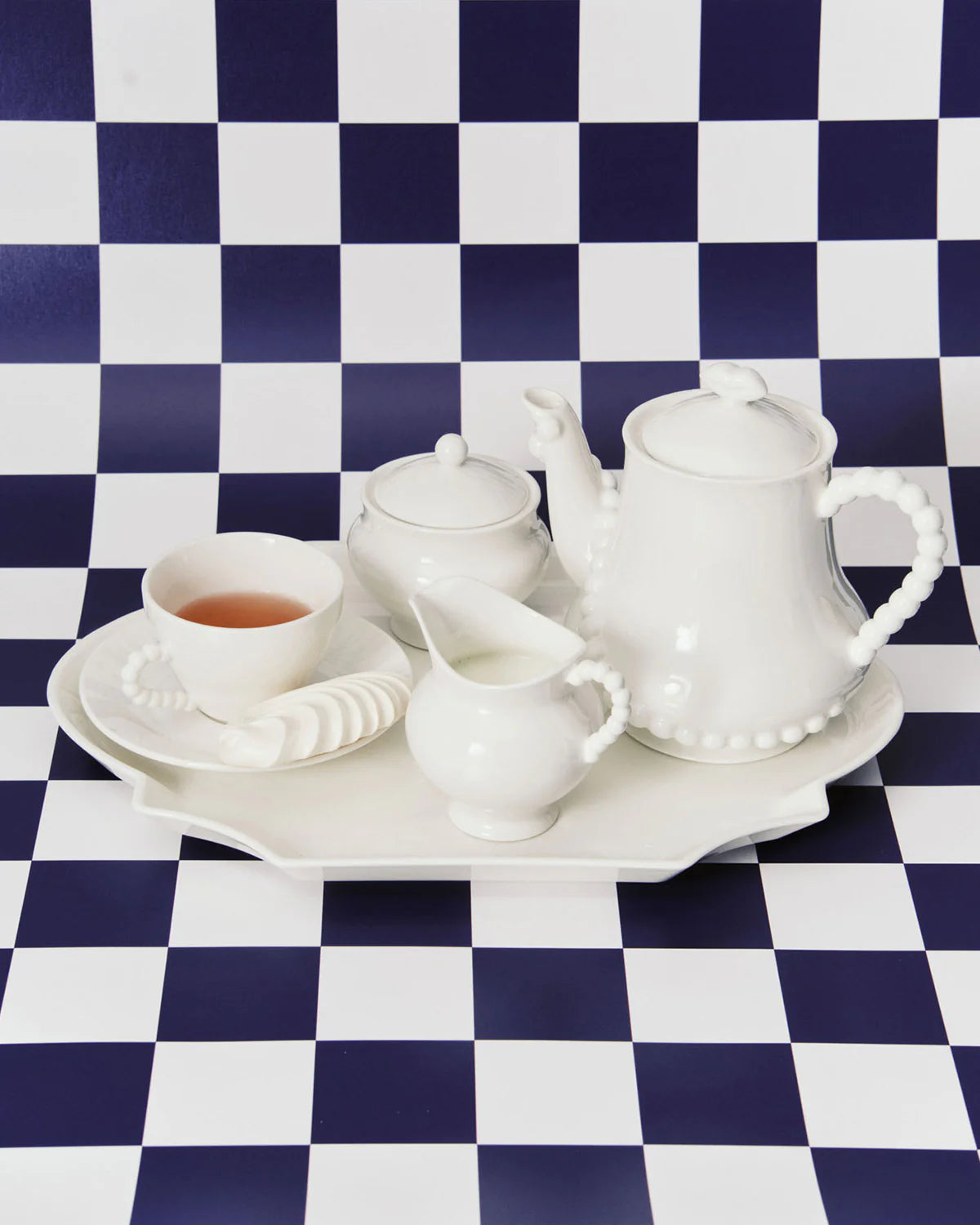 White ceramic tea set on a checkered blue and white tablecloth