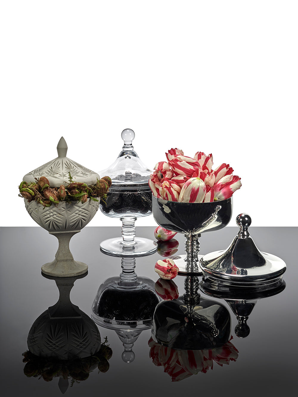 Decorative glass containers with lids on a reflective surface