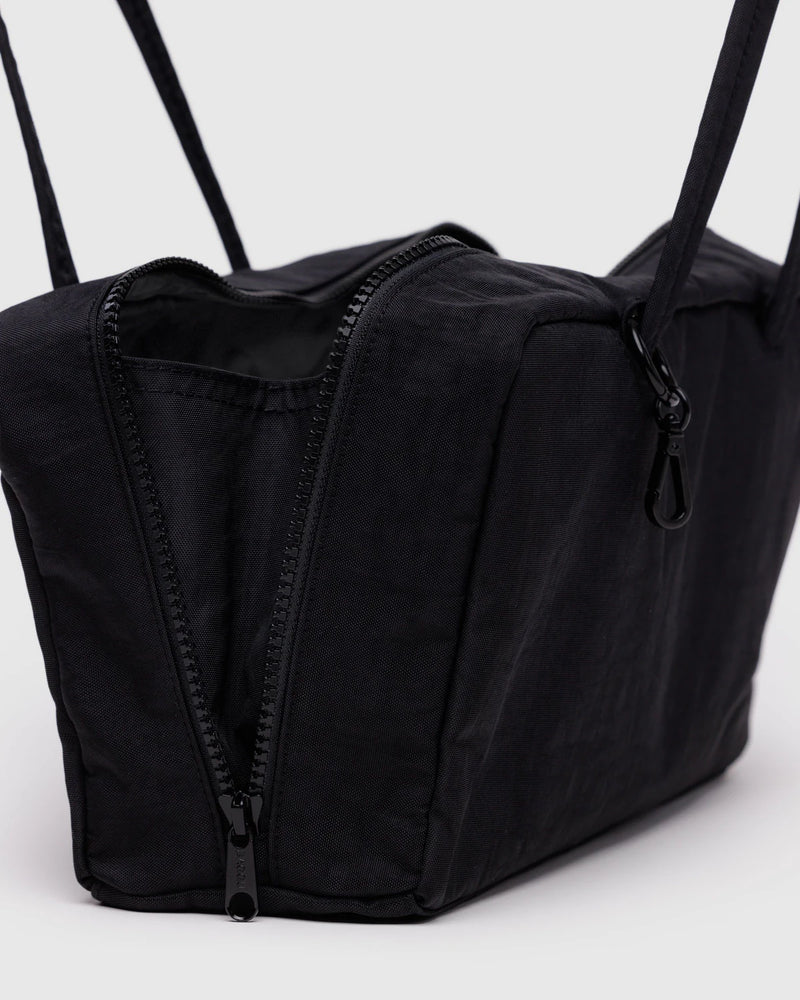Black duffel bag with straps on a light gray background