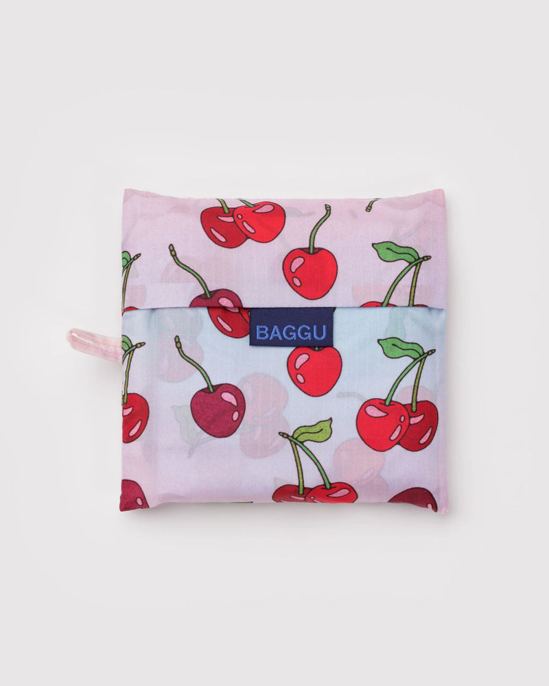 Reusable bag with cherry pattern and 'Baggu' brand logo on a light pink background