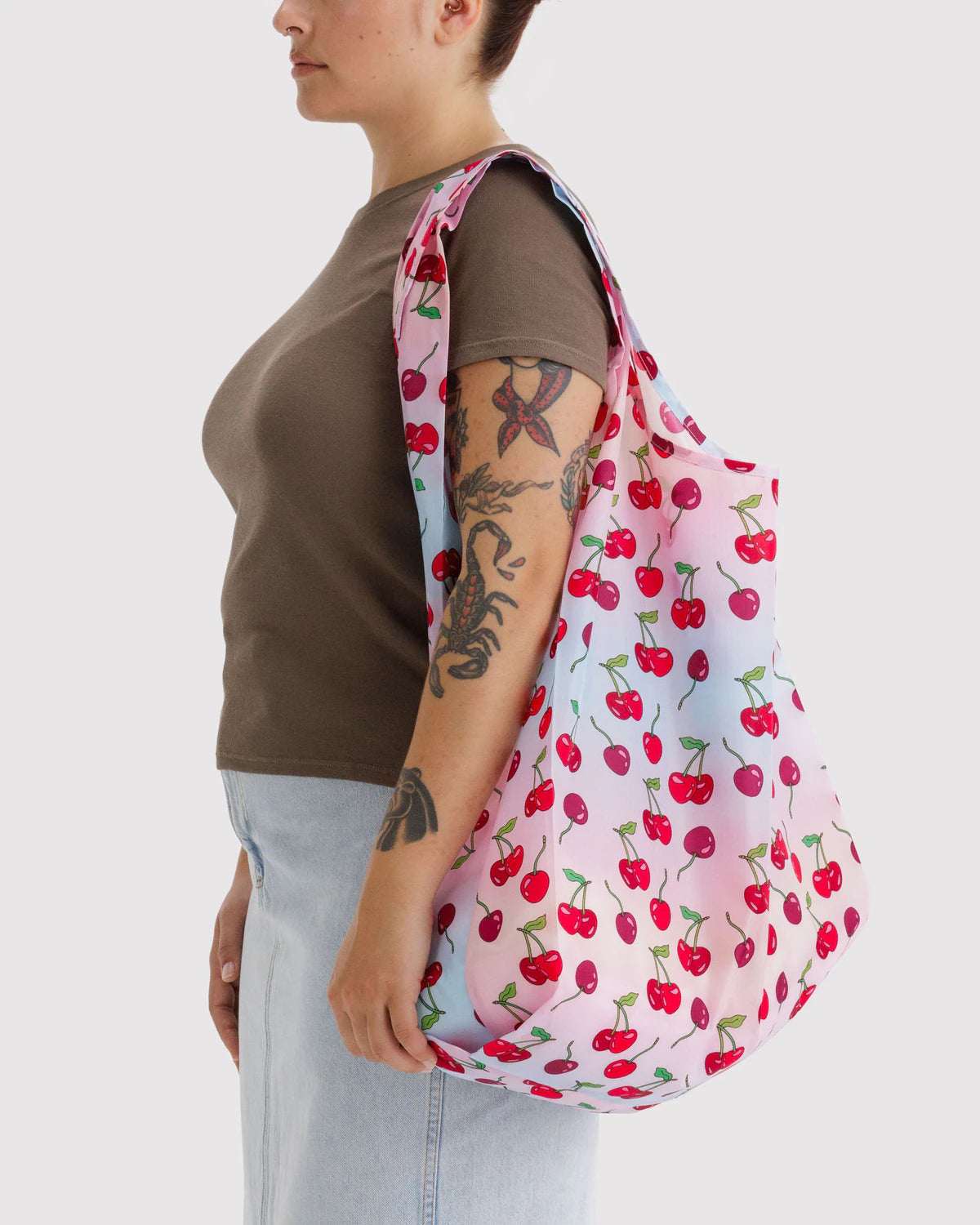 Person holding a cherry-patterned reusable bag against a white background