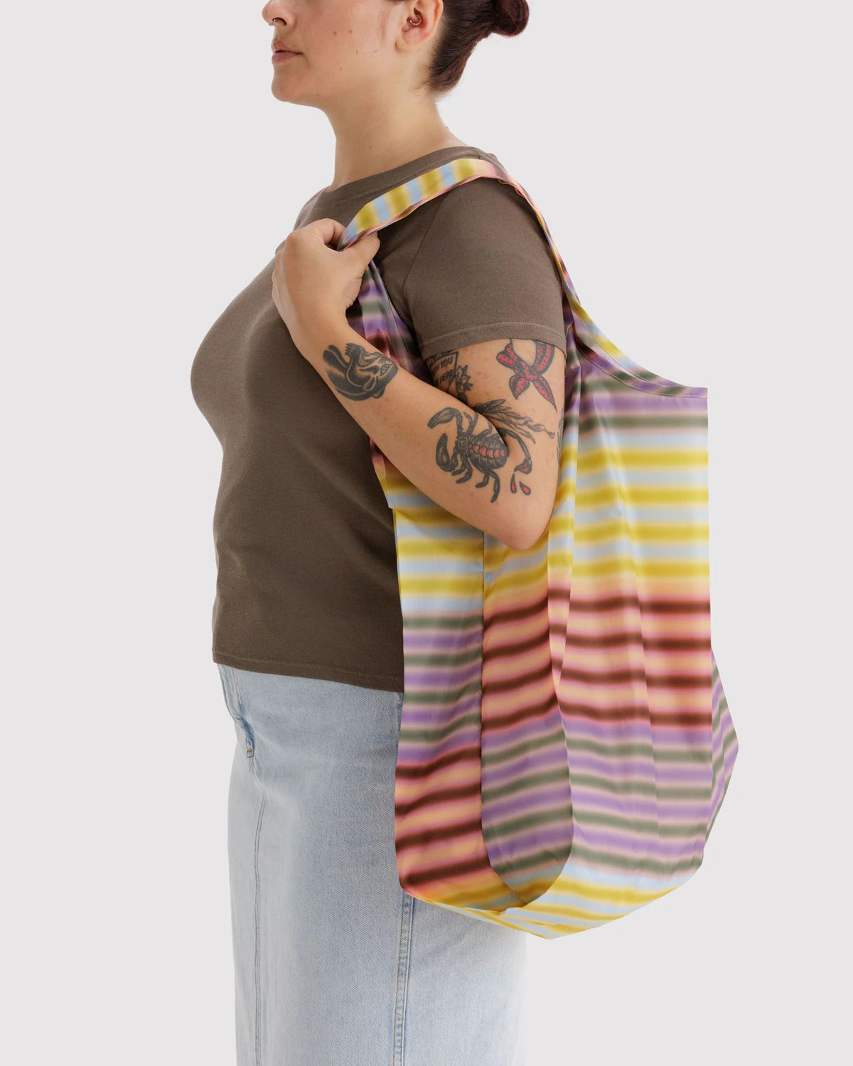 Person holding a colorful striped bag over their shoulder on a white background