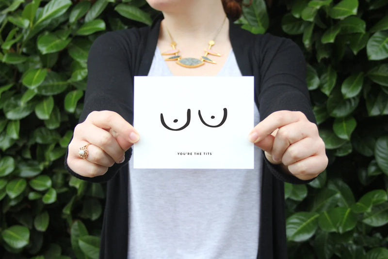 Person holding a card with niples and text against a green leafy background