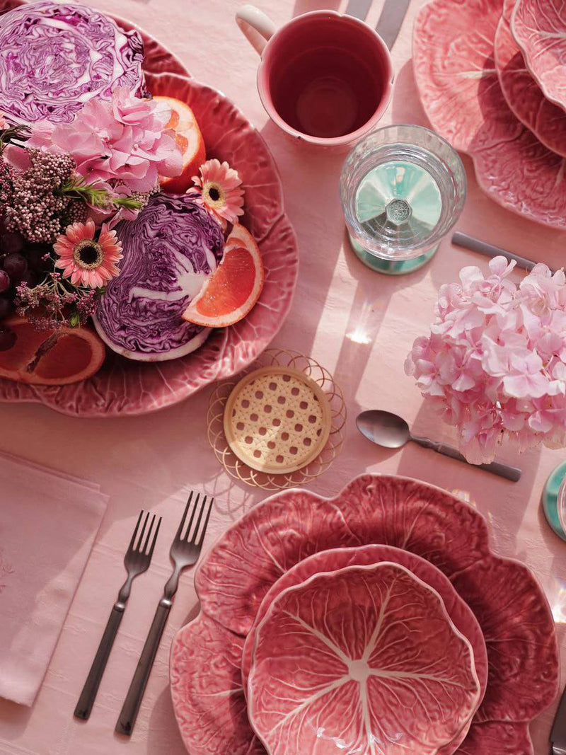 Pink and purple table setting with floral decorations and cutlery.