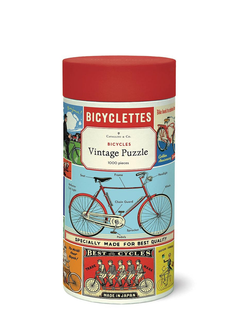 Packaging of a vintage puzzle featuring bicycles with 1000 pieces. The container is cylindrical with a red lid and displays an illustrated image of a bicycle and vintage-style text.