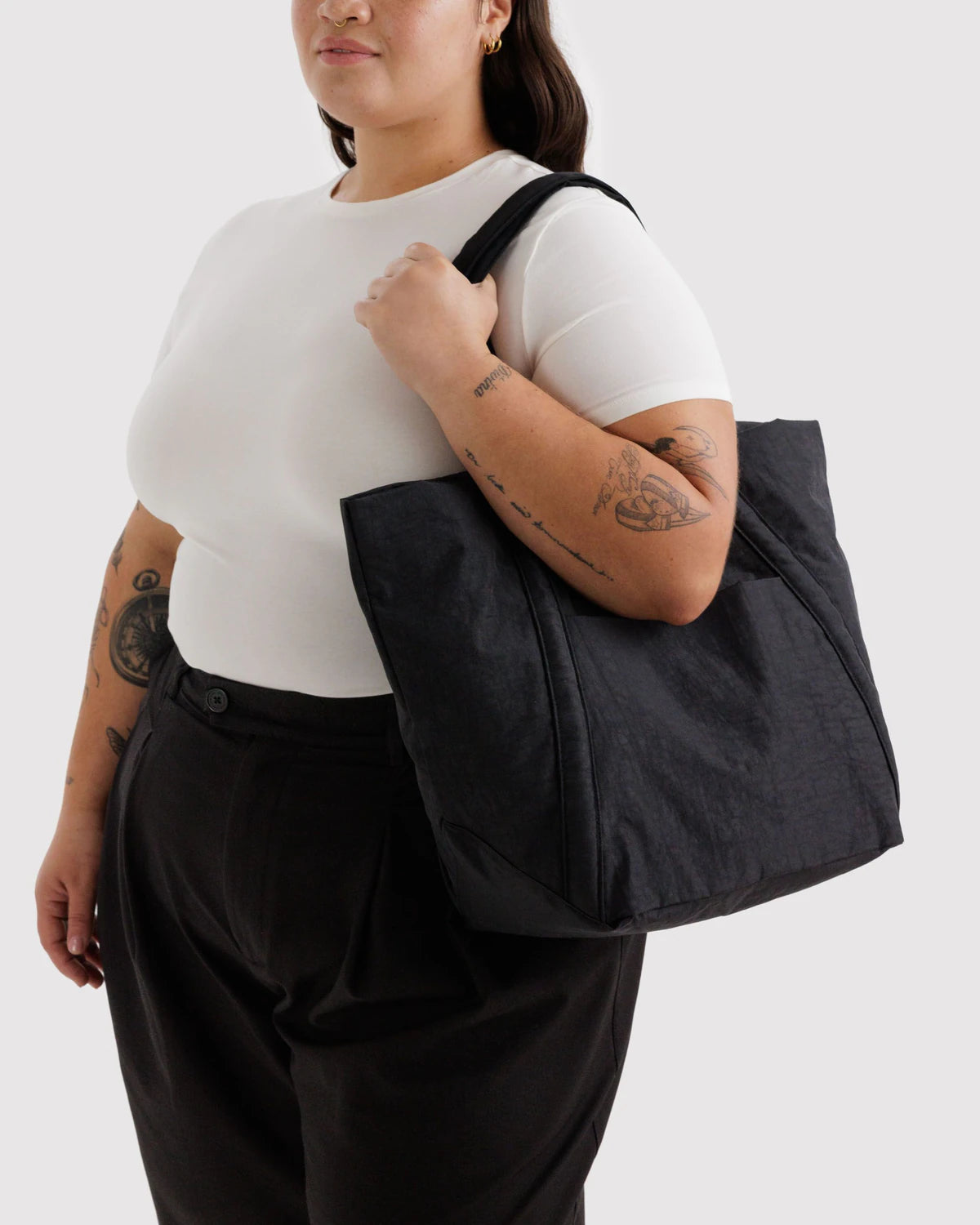 Person holding a black tote bag against a white background