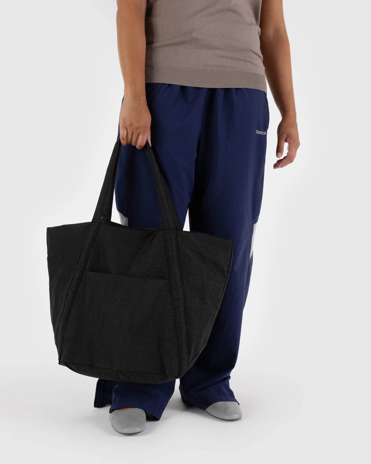 Person holding a black tote bag against a white background