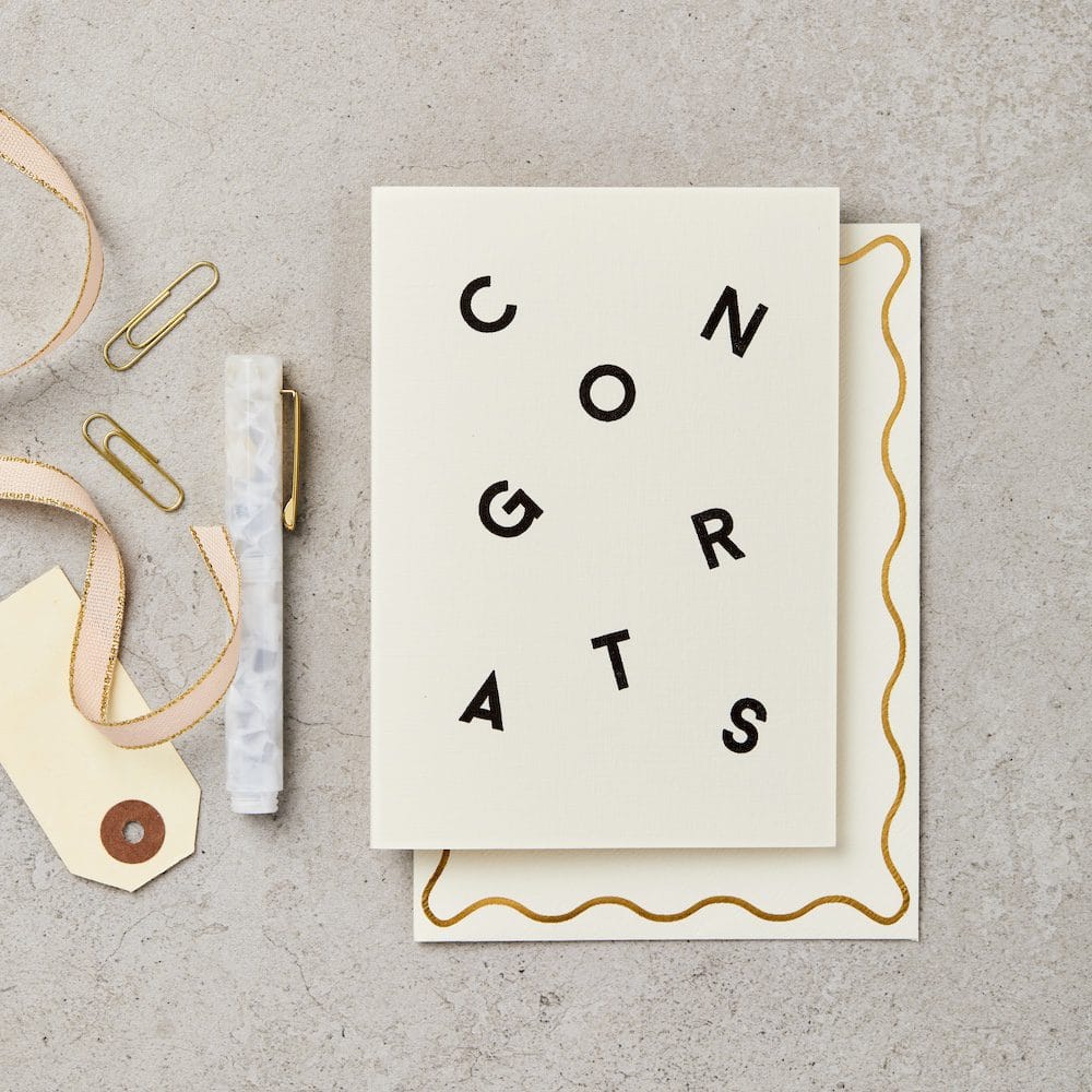 Greeting card with 'CONGRATS' text on a textured surface with decorative items.