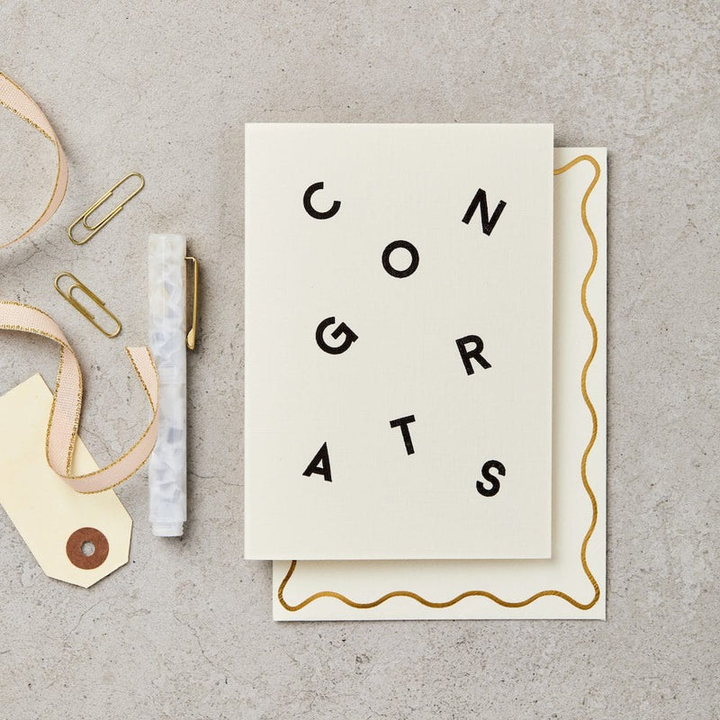 Greeting card with 'CONGRATS' text on a textured surface with decorative items.