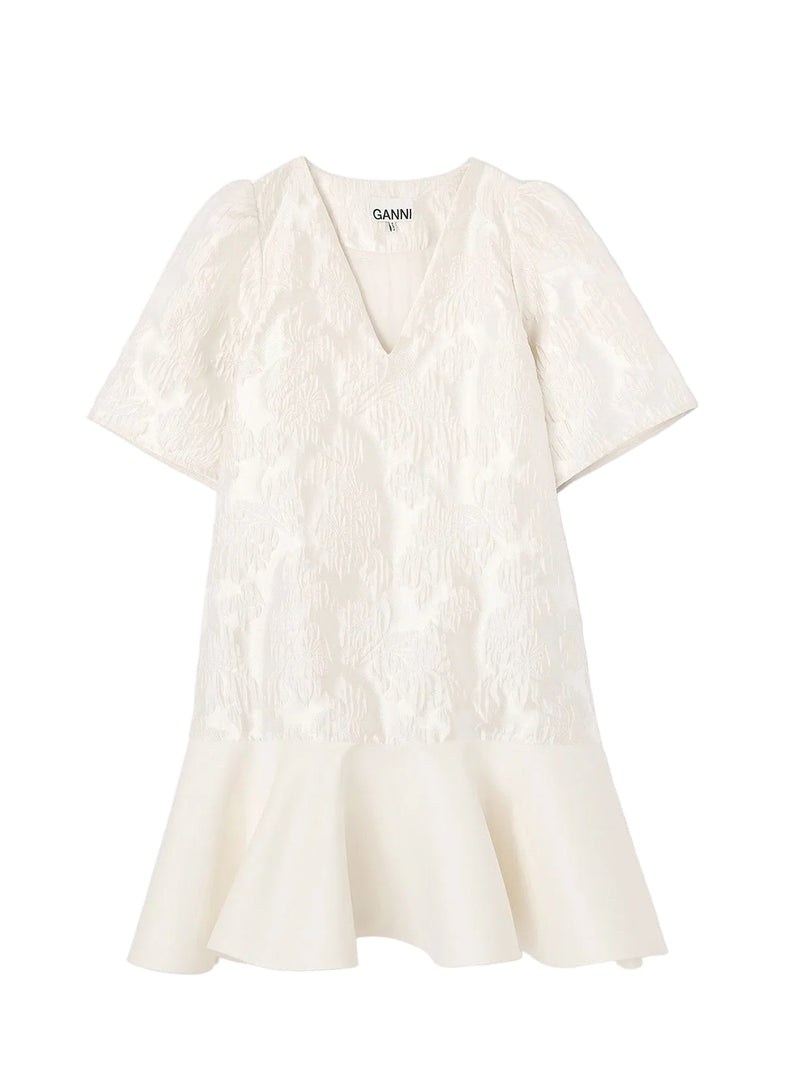 White textured dress on a light gray background with 'Ganni' branding.