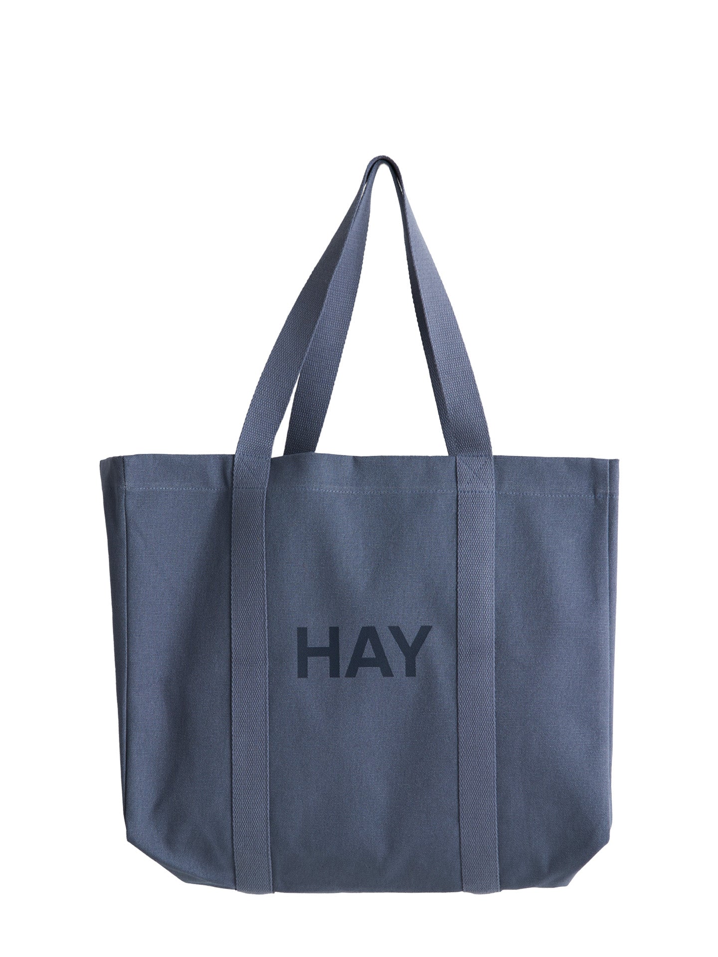 A slate blue canvas tote bag with 'HAY' printed in dark gray on the front, featuring dual shoulder straps, set against a plain white background.