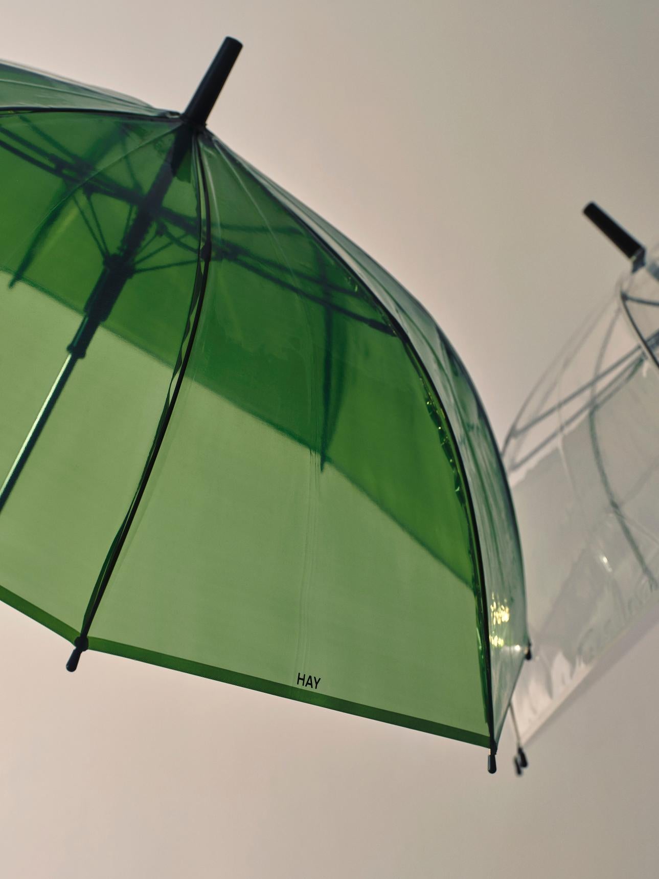 Green umbrella with black handle and ribs against a white background