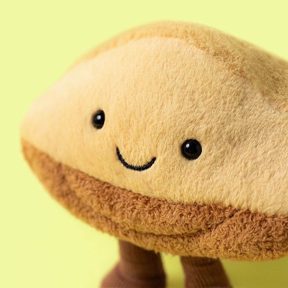 Plush toy resembling a pastry with a smiley face on a yellow background