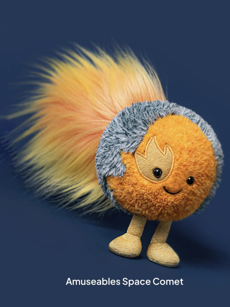 Plush toy resembling a space comet with a blue and orange design on a dark background