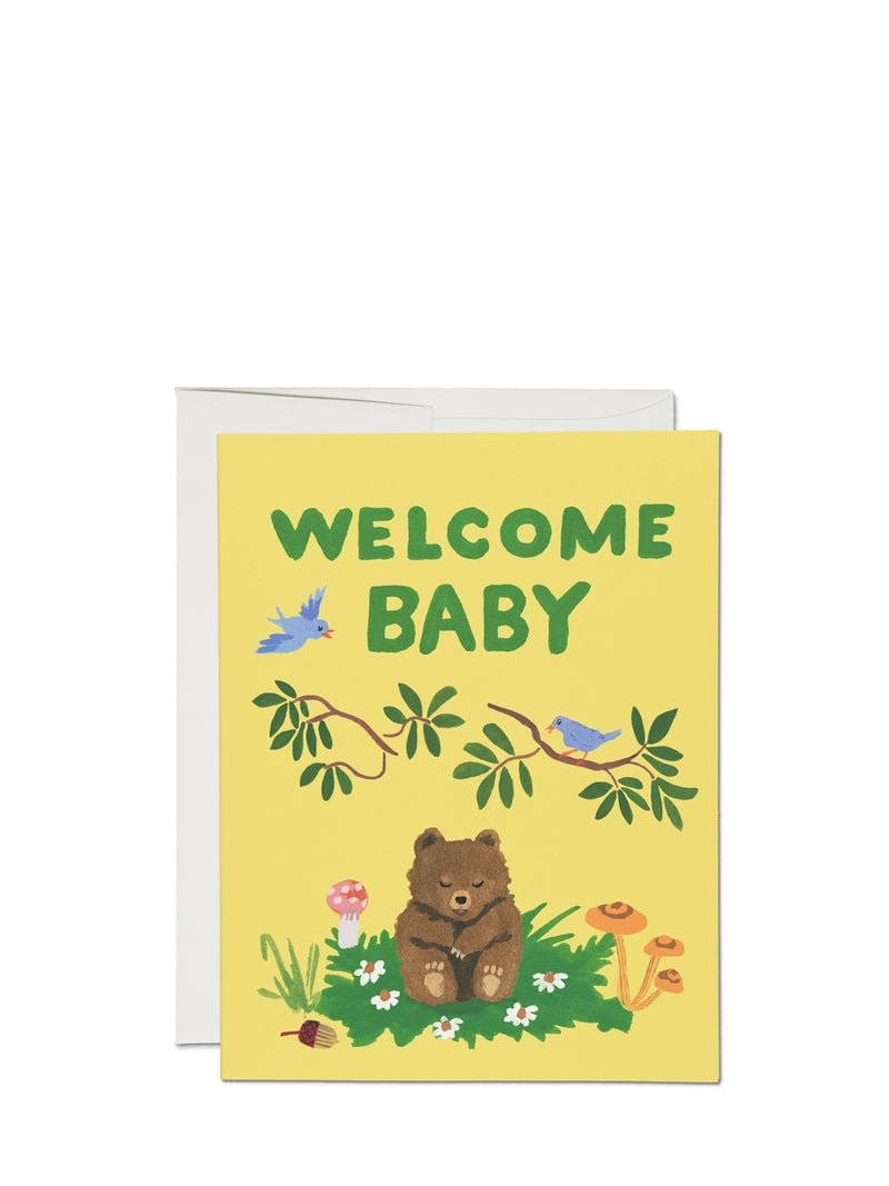A yellow greeting card with the text 'WELCOME BABY' at the top, featuring an illustration of a bear, birds, and flowers.