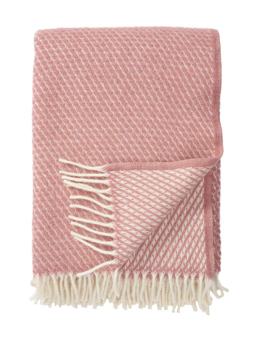 Pink woven throw blanket with white fringe on a white background