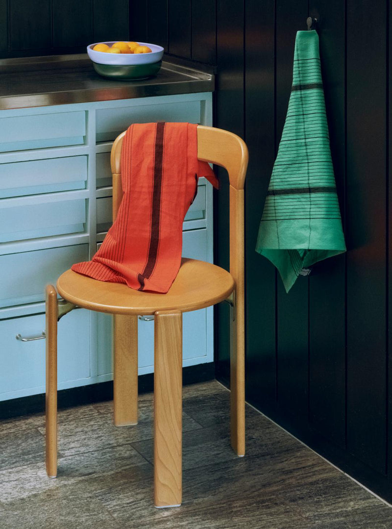 Wooden chair with an orange towel draped over it in a kitchen setting.