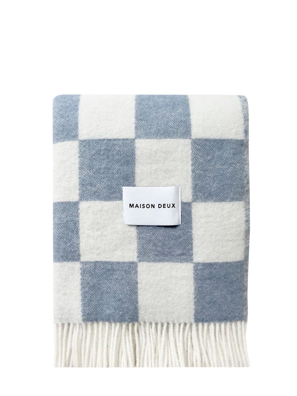 Checkered blanket with blue and white pattern and 'Maison Deux' label on a white background