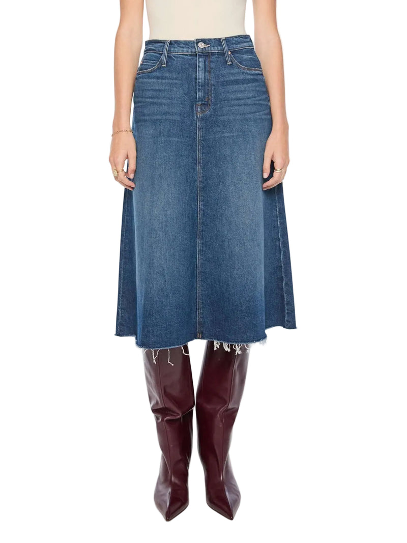 A model wearing a mid-length blue denim skirt with a raw, frayed hem, paired with dark burgundy leather knee-high boots against a plain white studio background.