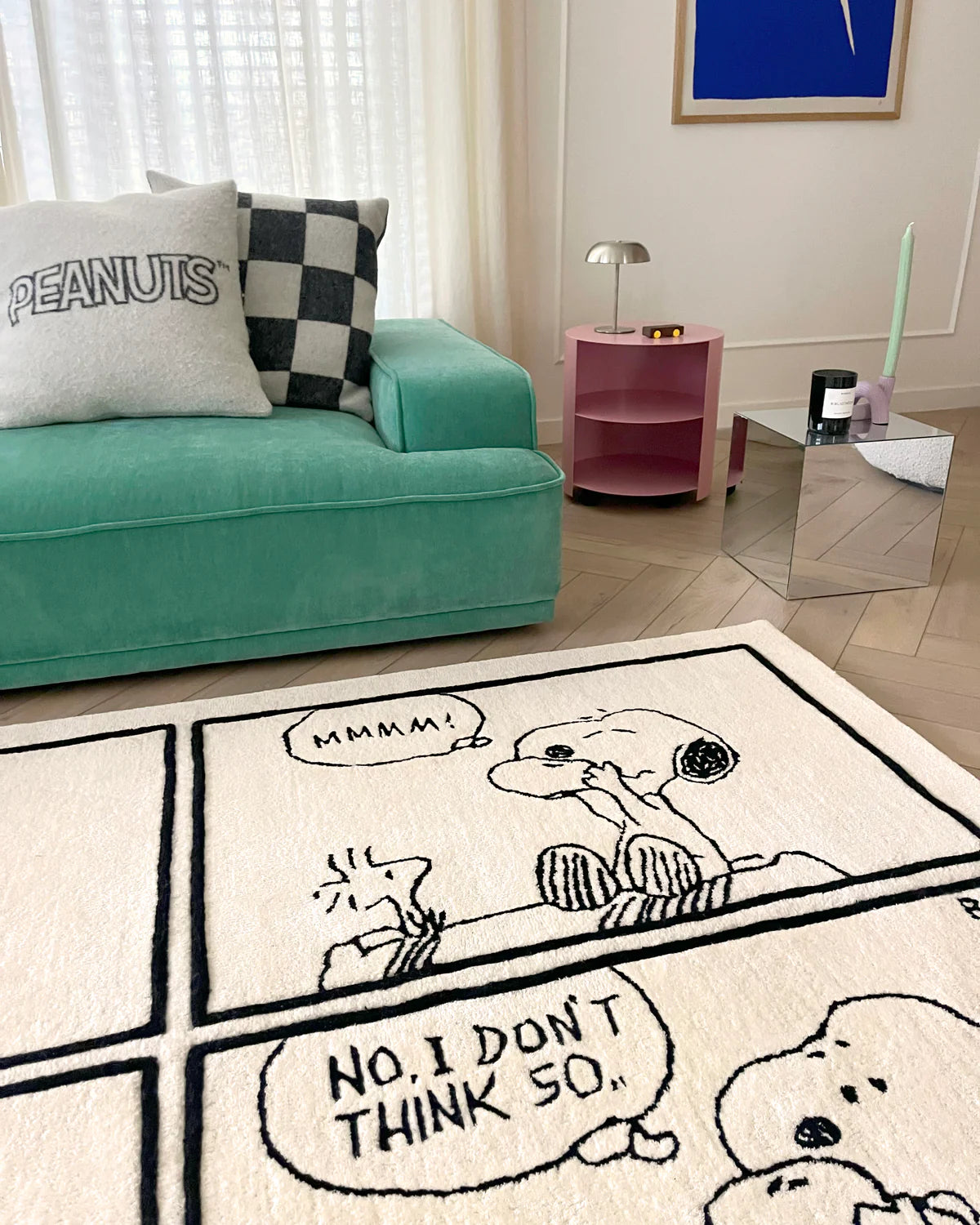 Living room with a teal sofa and a Snoopy-themed rug featuring comic-style text.