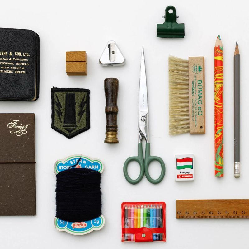 Collection of stationery items including scissors, pencils, and clips on a white background