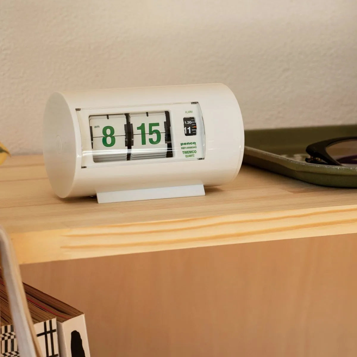 White flip clock with green numbers on a wooden surface