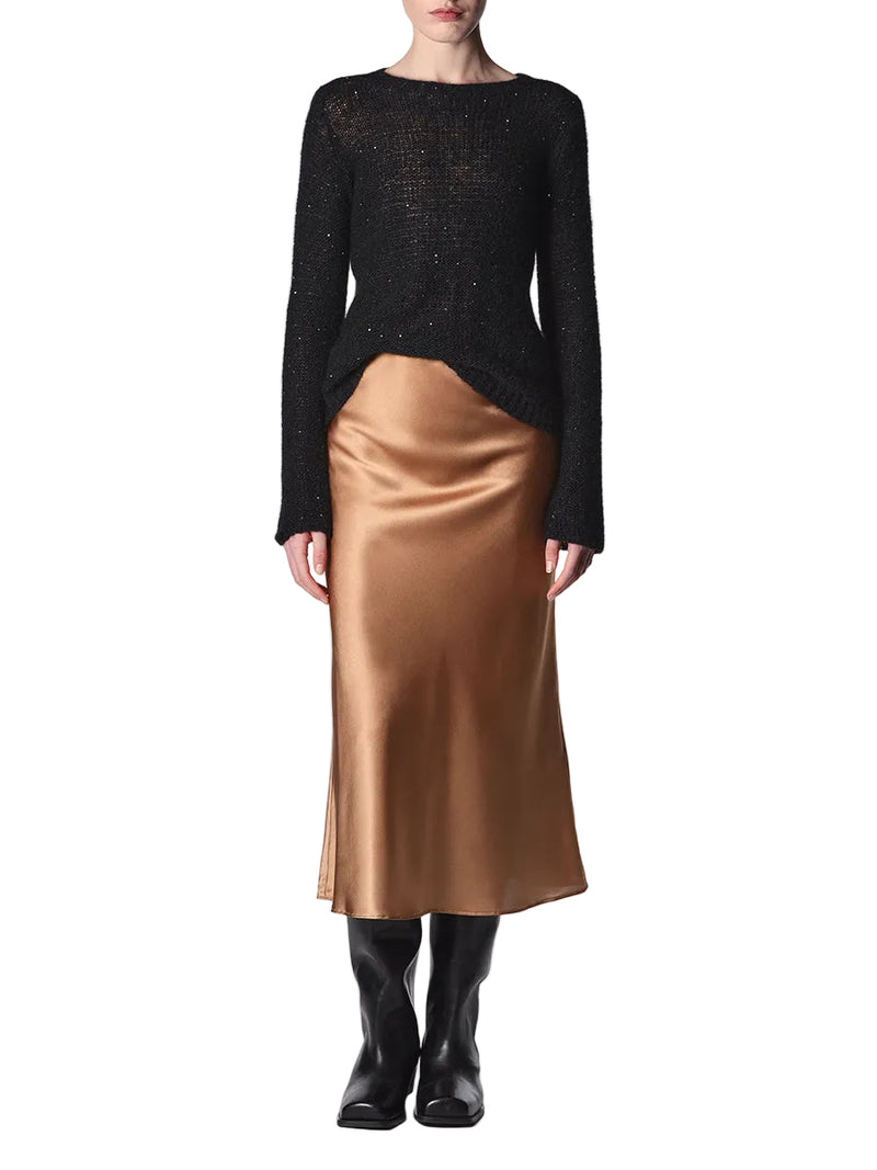 Person wearing a black sweater and gold satin skirt on a white background