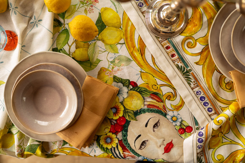 Decorative table setting with ceramic plates, a napkin, and a colorful tablecloth featuring a face design.