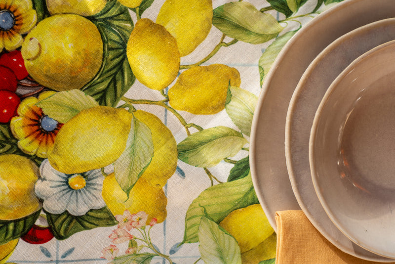 Stack of beige bowls on a tablecloth with lemon and floral pattern