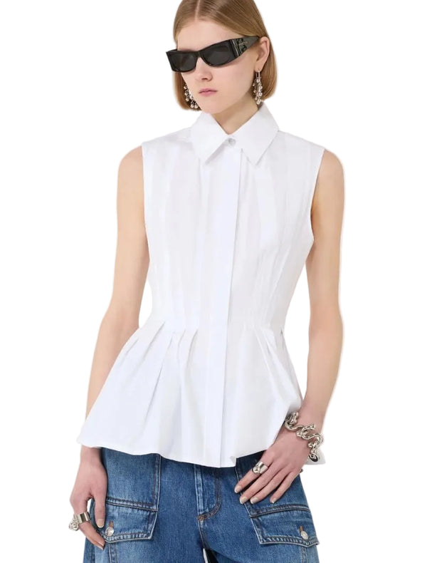Woman wearing a white sleeveless blouse and blue jeans on a white background