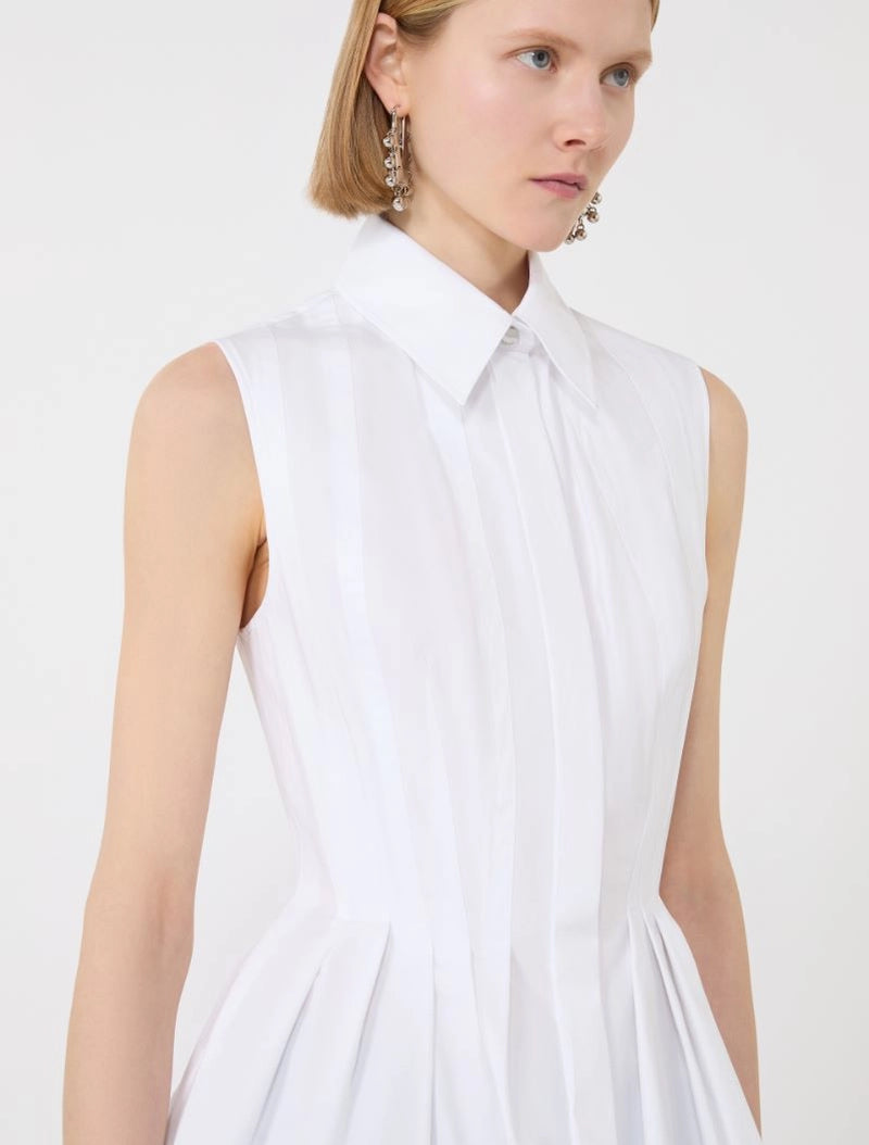 Woman wearing a white sleeveless dress against a plain background