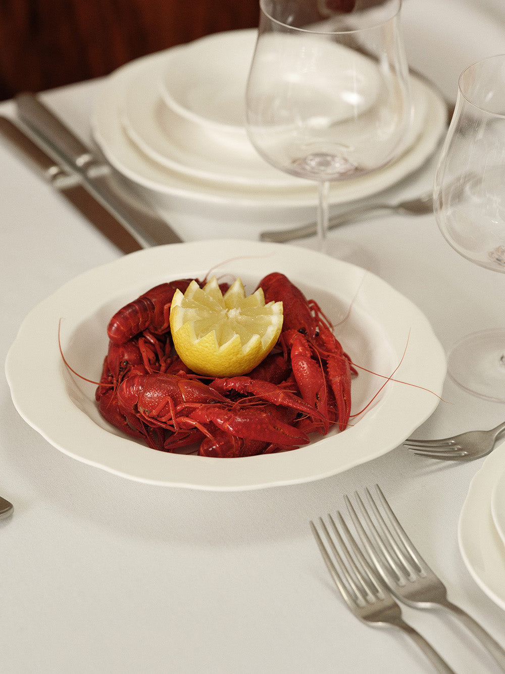 Crawfish on a white plate with a lemon wedge, set on a dining table.