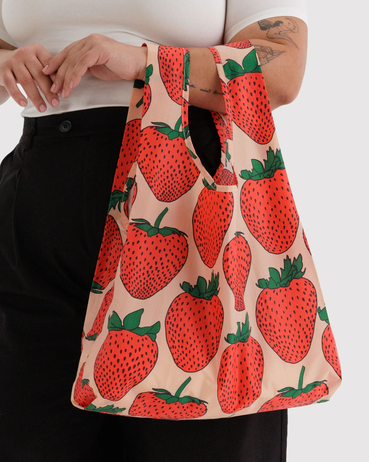 Person holding a reusable shopping bag with strawberry pattern